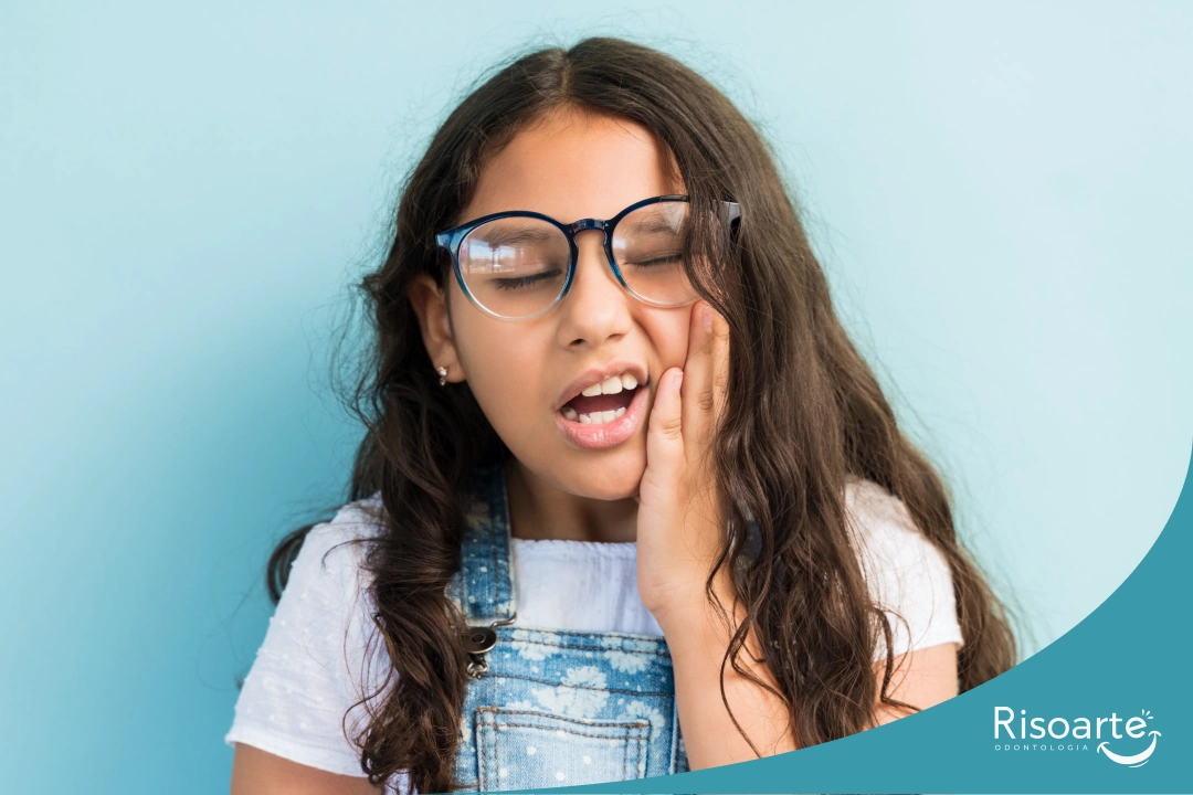 Menina com dor de dente colocando a mão no rosto