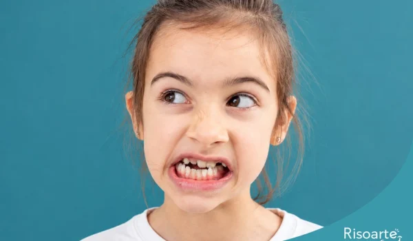 Criança mostrando os dentes durante o desenvolvimento infantil com sinais de Bruxismo.
