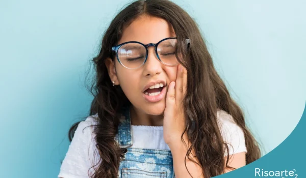 Menina com dor de dente colocando a mão no rosto